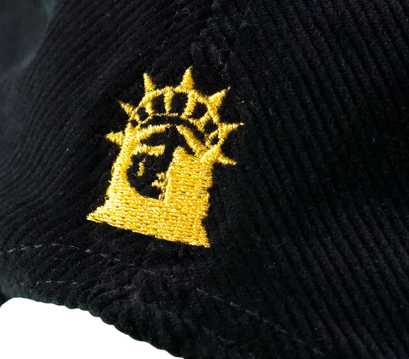 Macro: the back of the cap — a small gold embroidered Statue of Liberty, head bowed, above the snap closure